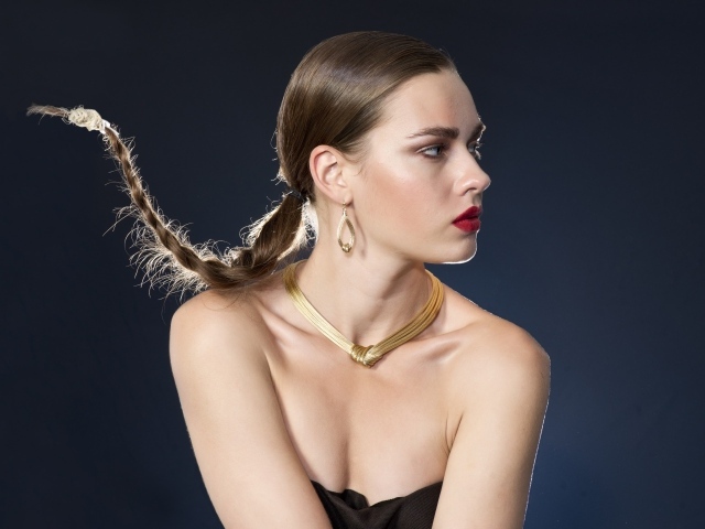 Красивая девушка с косой на голове на сером фоне