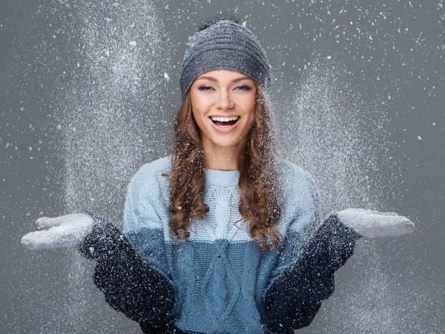 Красивая улыбающаяся девушка ловит снег руками