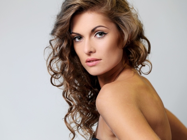 Красивые волнистые волосы девушки на сером фоне