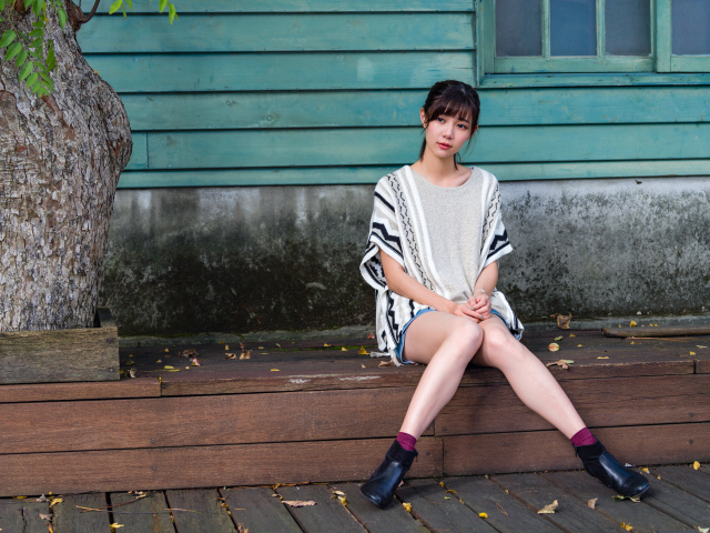 Красивая молодая девушка азиатка сидит у дома