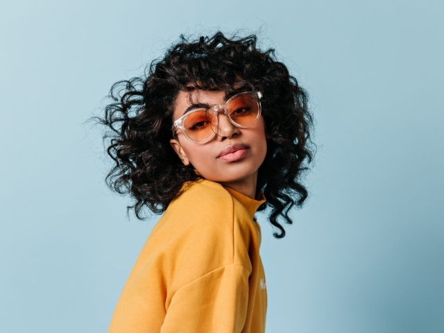 Темнокожая девушка в очках на голубом фоне фоне