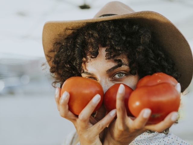 Девушка в шляпе с помидорами в руках 