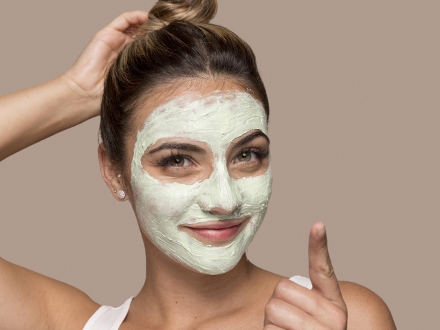 Девушка с завязанными волосами с косметической маской на лице