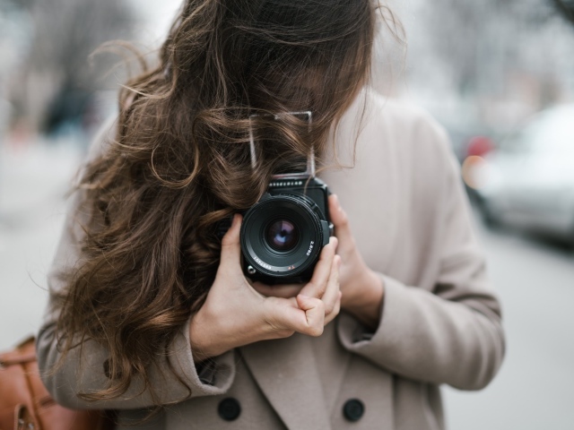 Длинноволосая девушка с фотоаппаратом в руках 