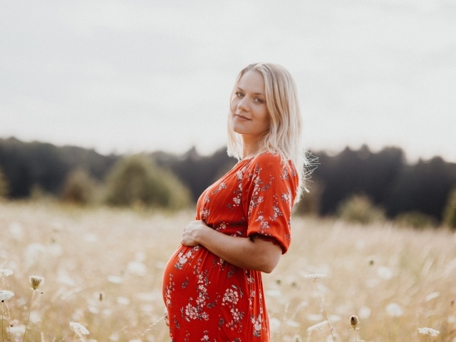 Беременная девушка в красном платье на поле