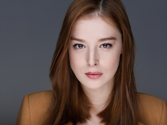 Рыжеволосая  молодая девушка на сером фоне