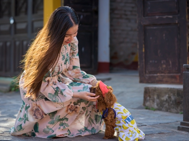 Улыбающаяся девушка азиатка с собакой 