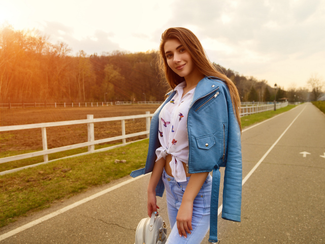 Улыбающаяся девушка в синей кожаной куртке на дороге 