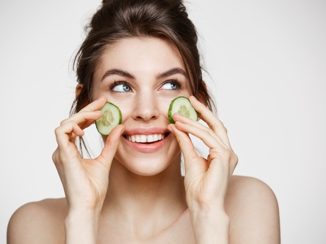 Улыбающаяся девушка с огурцами на лице