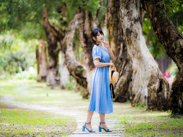 Стильная девушка азиатка в голубом платье в парке 
