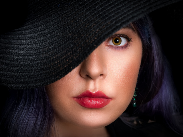 Глаз девушки закрыт черной шляпой 