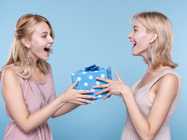Две веселые подруги с подарком на голубом фоне