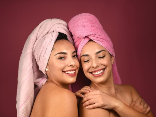 Две девушки с полотенцами на голове на красном фоне 