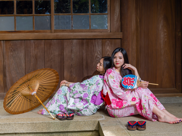 Две молодые девушки в кимоно сидят на полу