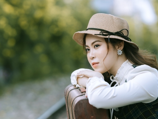 Молодая азиатка в шляпе с чемоданом