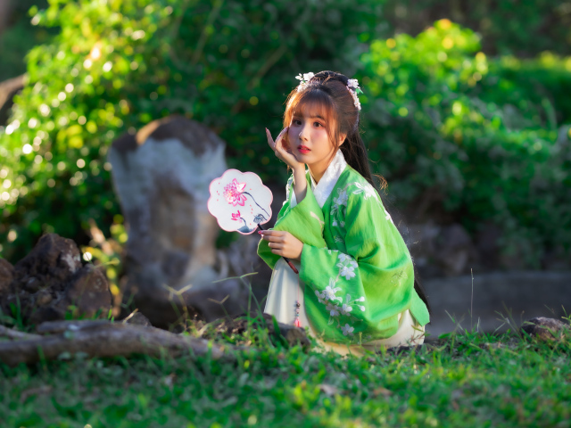 Молодая азиатка в кимоно сидит в парке