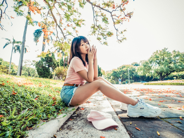 Молодая азиатка сидит на земле в осеннем парке