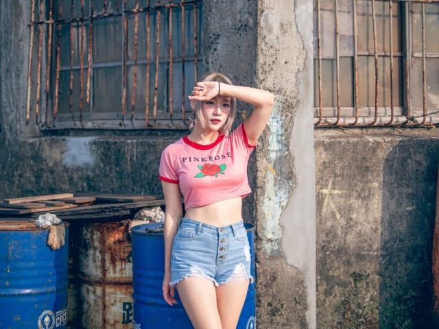 Молодая азиатка стоит у стены 