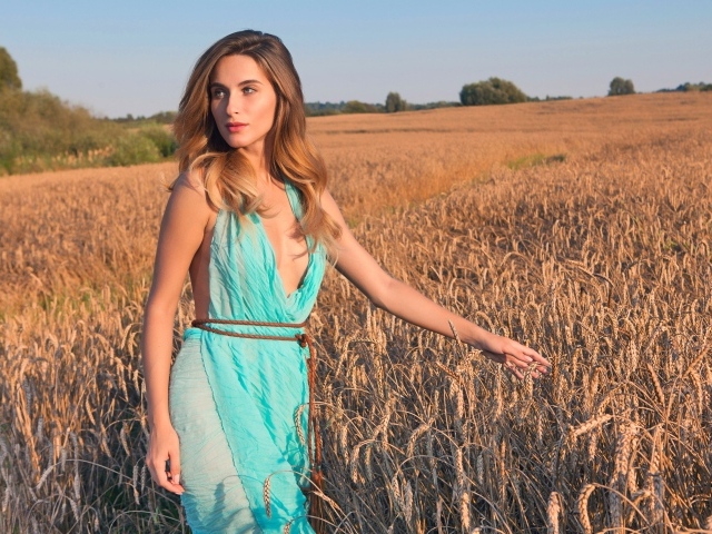 Молодая девушка в голубом платье на поле с пшеницей 