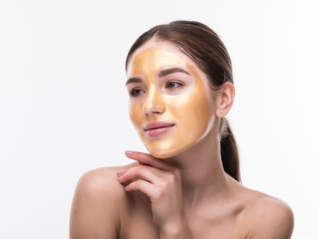 Молодая девушка без макияжа с золотой маской на лице