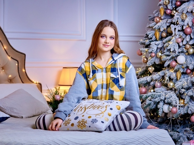 Милая девушка на кровати у новогодней елки 