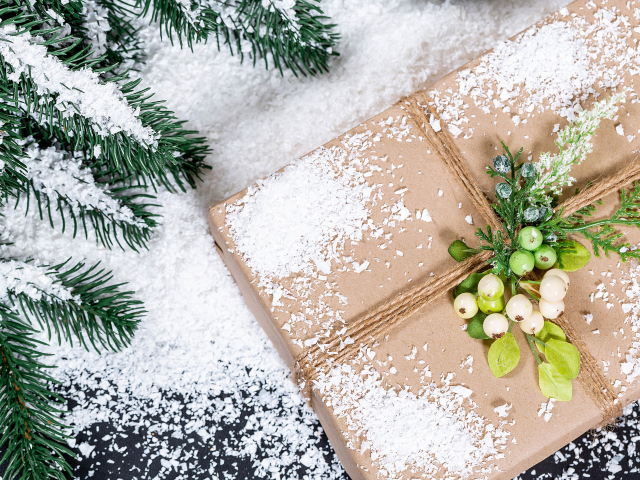 Подарок с заснеженной веткой ели на столе