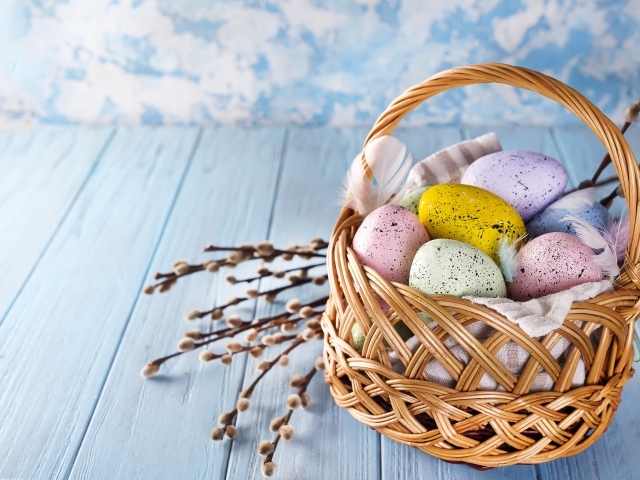 Корзина разноцветных крашеных яиц с ветками вербы на Пасху 2021 