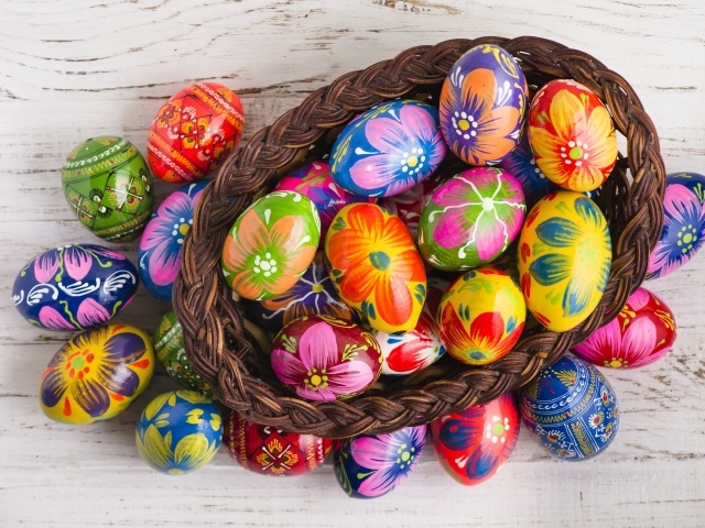 Красивые крашеные яйца в корзине на столе на праздник Великой Пасхи