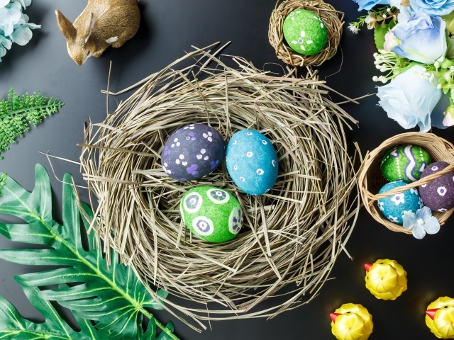 Яркие пасхальные яйца на столе в гнезде