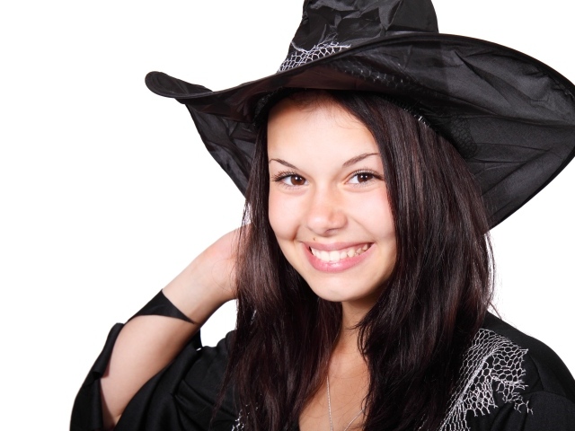 Улыбающаяся девушка в костюме ведьмы на Хэллоуин