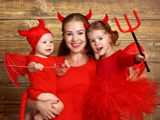 Женщина с двумя детьми в красных костюмах на Хэллоуин