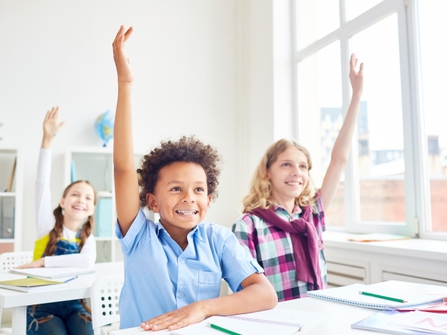 Дети школьники с поднятой  рукой в классе на 1 сентября 
