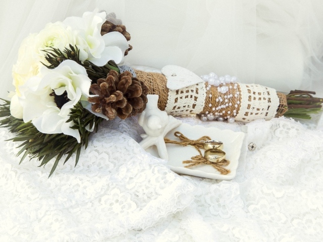 Букет невесты из цветом анемоны лежит на платье с обручальными кольцами