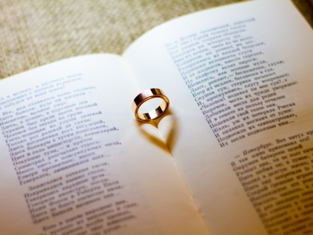 Золотое обручальное кольцо лежит на открытой книге