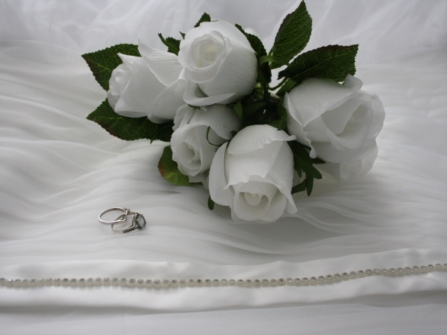 Белые бутоньерки с кольцами на белом покрывале 