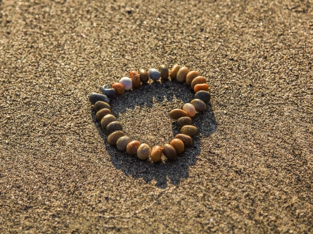 Сердце из мелкий морских камей на песке 