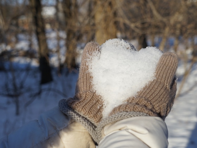 Снег в руках у девушки в перчатках 