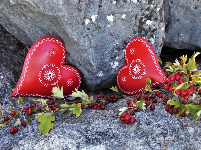 Два сердца лежат у камня с красными ягодами