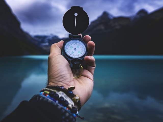 Компас в руке у мужчины на фоне гор 