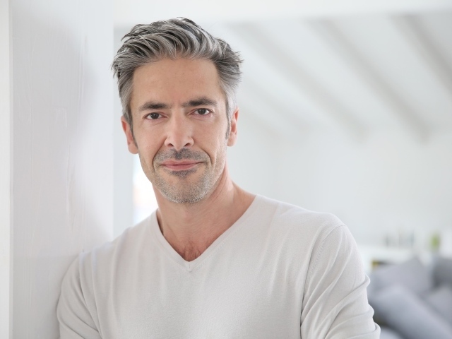 Седой стильный мужчина у стены