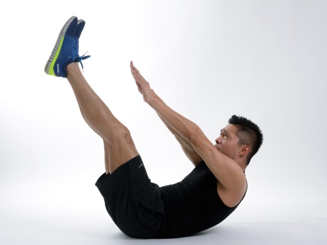 Мужчина спортсмен качает пресс на белом фоне