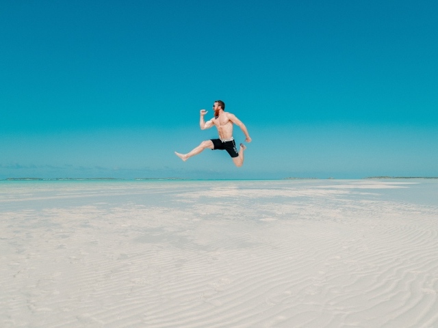 Довольный мужчина прыгает в воде на голубом фоне 