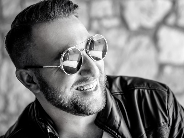 Улыбающийся брутальный мужчина в черных очках