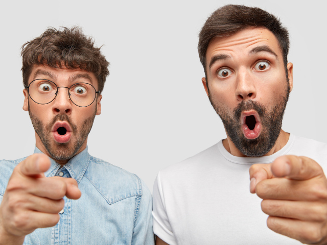 Два удивленных мужчины на сером фоне