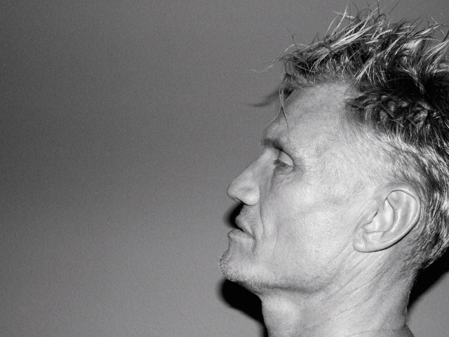 Лицо актера Дольфа Лундгрена боком на сером фоне