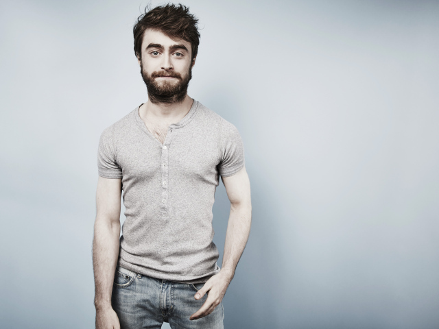 Популярный актер Дэниел Рэдклифф стоит у стены