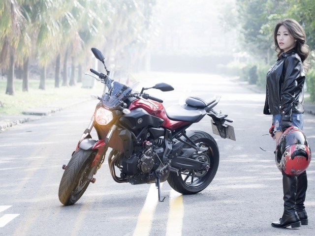 Девушка азиатка с мотоциклом стоят на дороге 