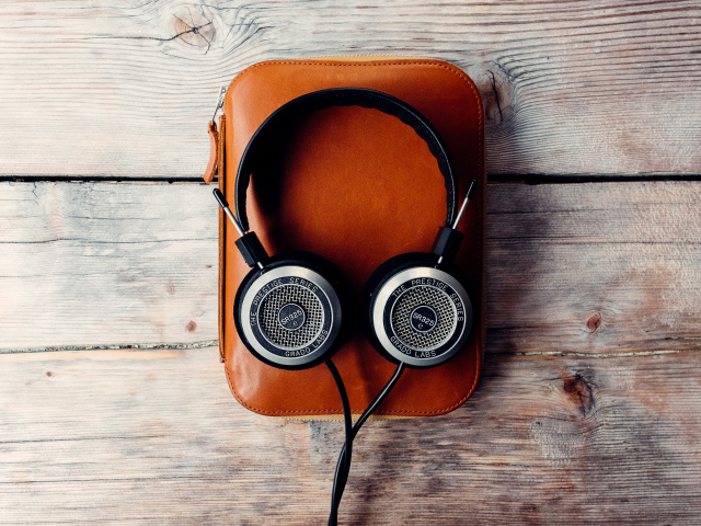 Наушники и плеер в чехле на деревянном столе