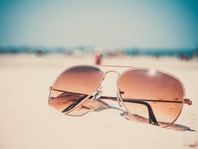 Солнечные очки лежат на горячем песке 