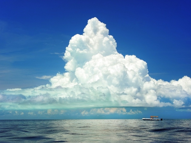 Большое белое облако в голубом небе над морем 